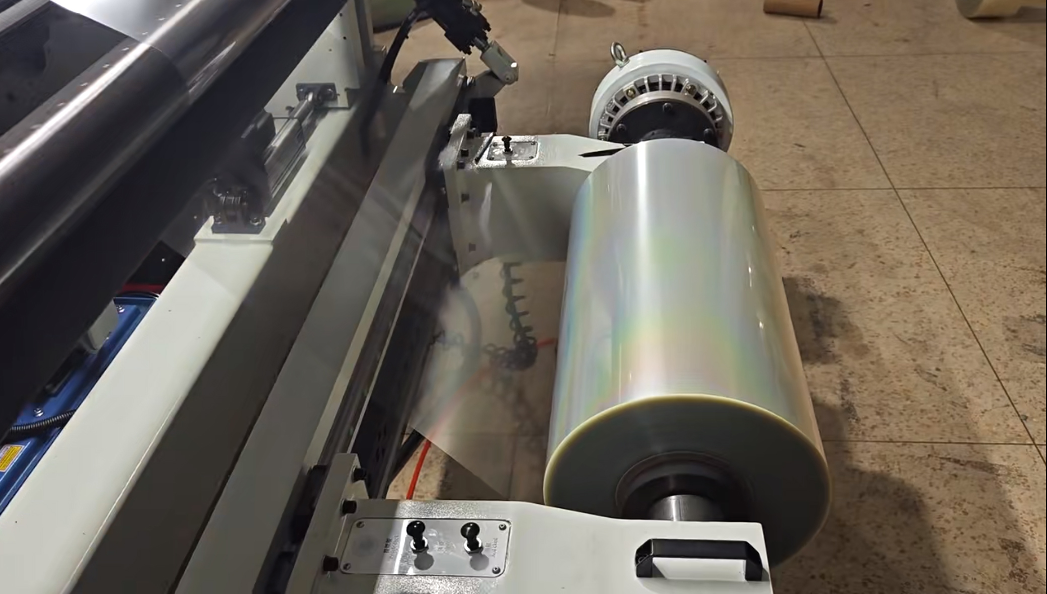 Close-up of GGIN slitting rewinder machine processing holographic film — showing circular slitting blade and precision surface rewinding mechanism